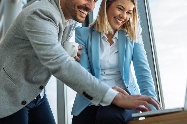 Mężczyzna i kobieta uśmiechający się do laptopa